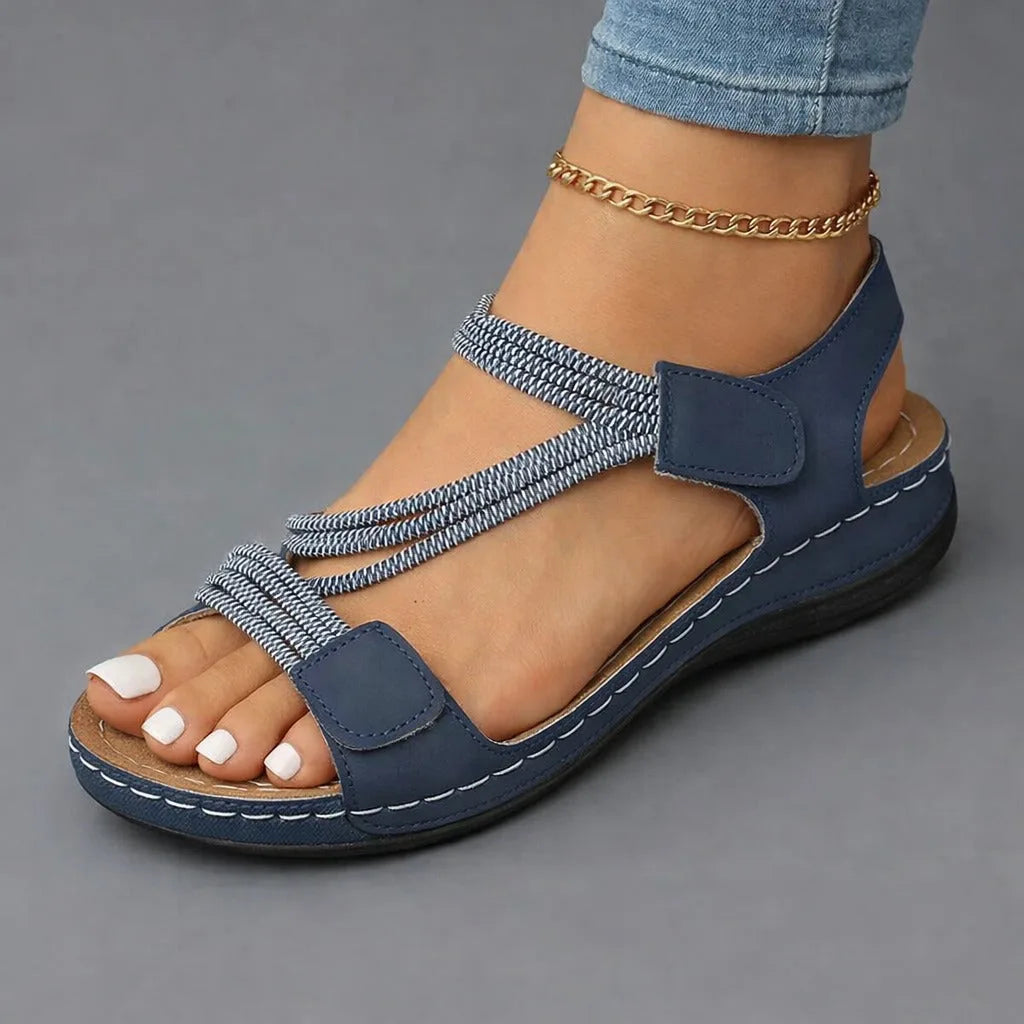 Front-angled view of navy strappy sandal highlighting the woven ankle strap and cushioned stitched footbed.