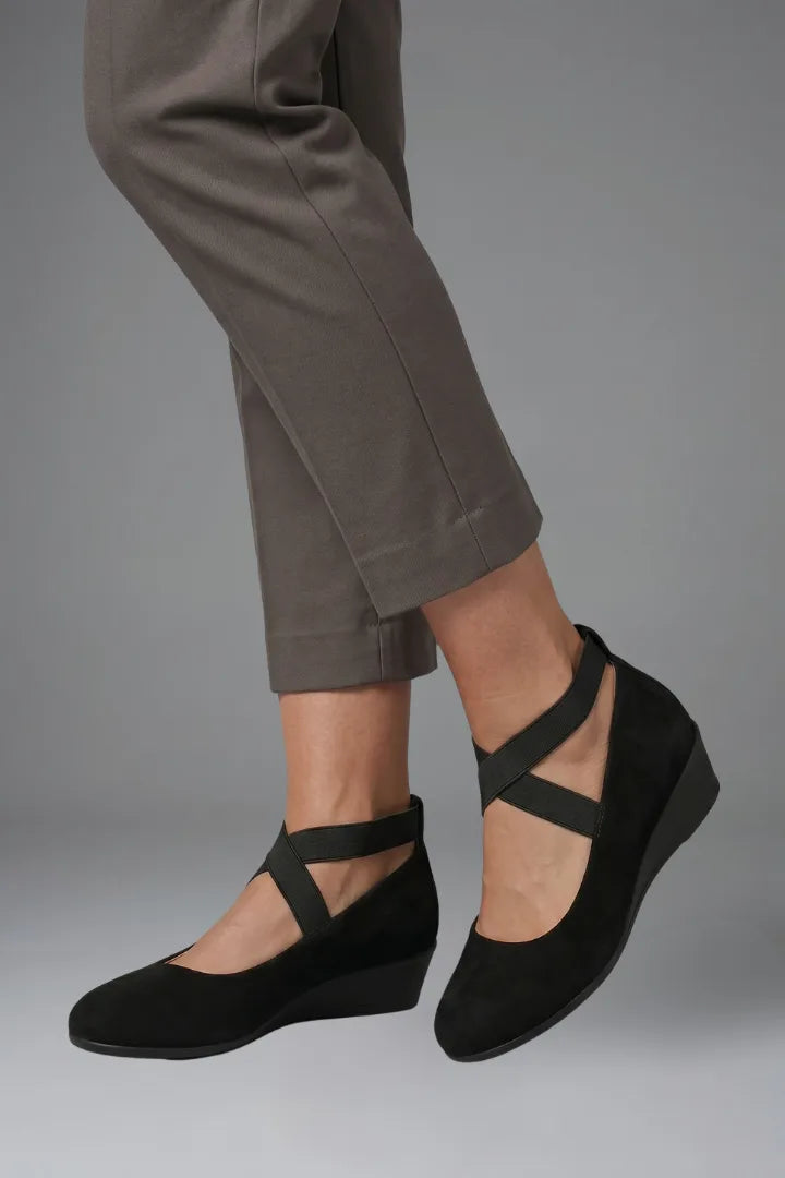 Close-up side profile of black suede wedge flats with elastic ankle straps and rounded toe