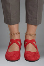 Front view of red suede ballet flats with crisscross elastic straps, paired with gold ankle chains
