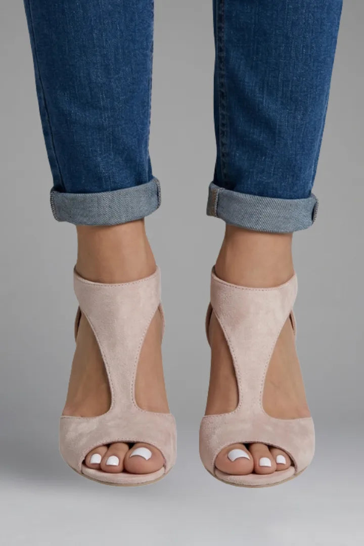 Close-up front view of pink suede peep toe heels paired with cuffed denim jeans