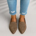 Front view of pointed-toe suede penny loafers in taupe worn with cuffed distressed skinny jeans