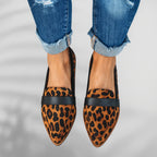 Top-down view of leopard-print loafers with black trim worn with cuffed denim jeans