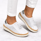 White suede slip-on sneakers worn with cuffed white jeans, showing the silver heel trim and woven-look cork midsole