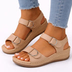 Close-up side view of beige strappy wedge sandal with silver buckle details, worn with cuffed jeans