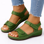 Green leather-look wedge sandal with hook-and-loop straps and perforated toe strap, worn on foot