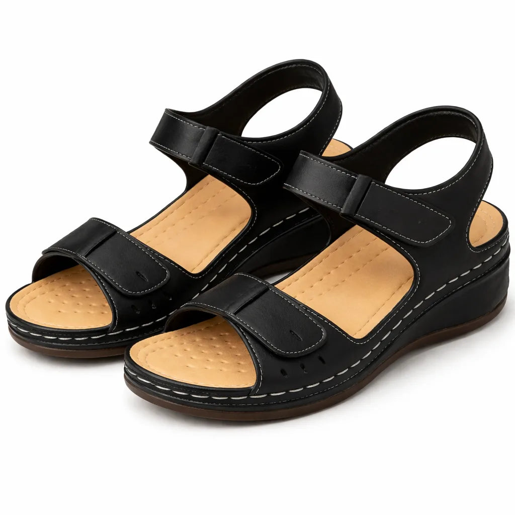 Studio pair shot of black wedge sandals showing tan cushioned footbed and stitched outsole detail