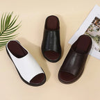 Side angle of black wedge slide resting flat, showing full platform height and sole grain