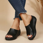 Black open-toe wedge slide shown on foot with chunky black platform heel, side profile view