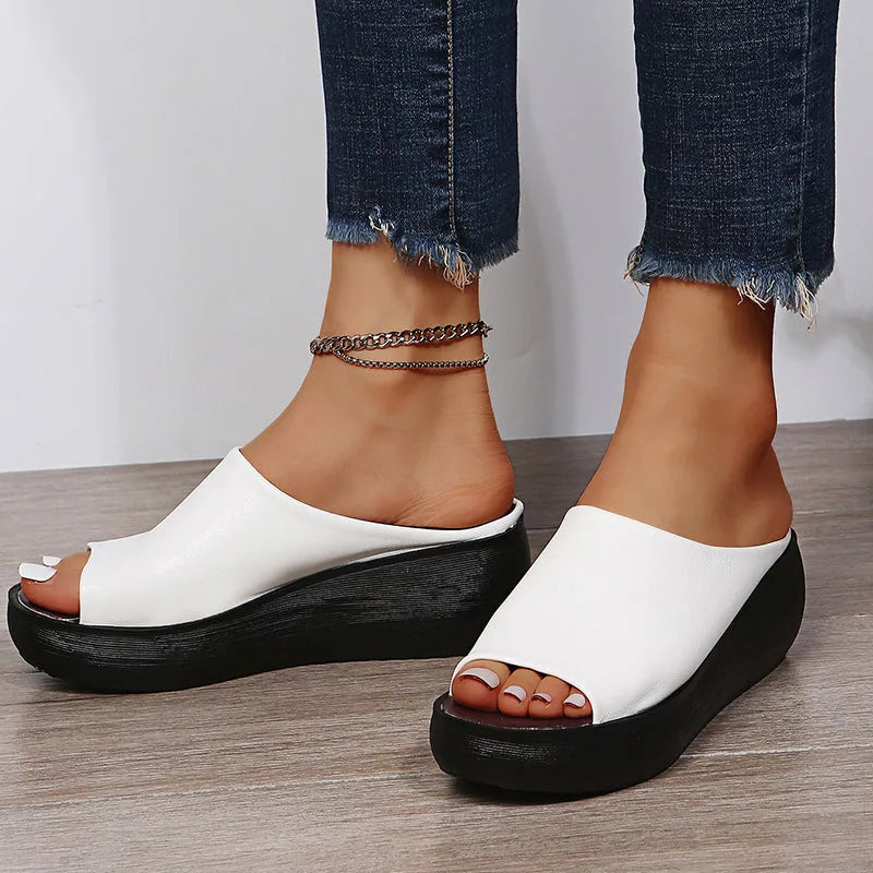 Side view of white wedge slides highlighting the curved toe opening and stacked black sole