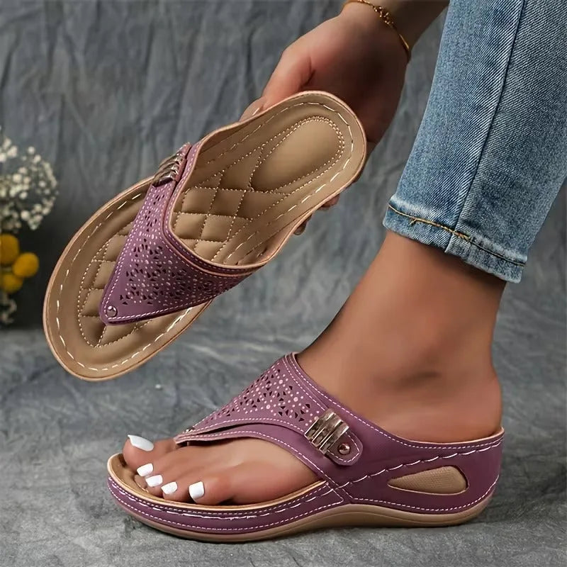 Black flip-toe wedge sandal with perforated upper and padded tan insole, held up to show cushioned footbed