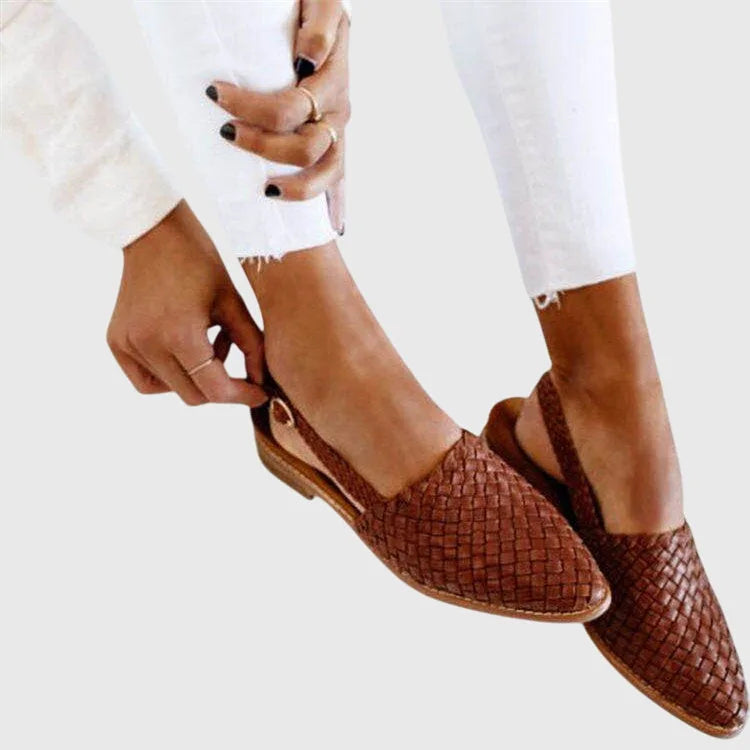 Hand adjusting the buckle on a brown woven leather slingback flat for a secure fit