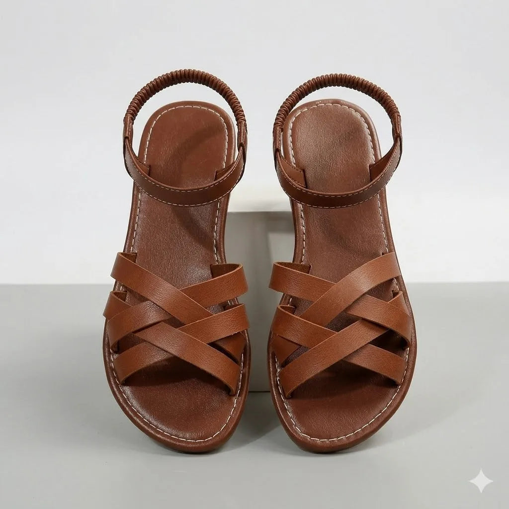 Front-facing view of a pair of brown crisscross strap flat sandals showing stitched footbed detail