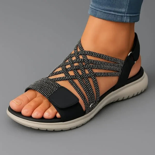 Black and white woven strap sandal with touch-fasten front panel and chunky white outsole, side angle view