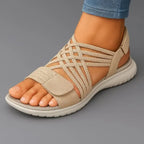 Beige strappy sandal with caged woven straps and suede-look toe panel, shown from the side on a bare foot