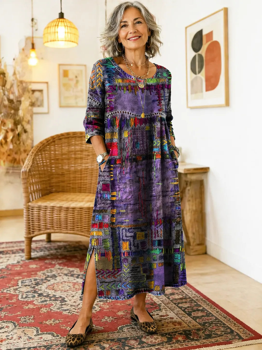 Model smiles in the purple patchwork-print dress, hand in the hip pocket, paired with layered gold necklaces