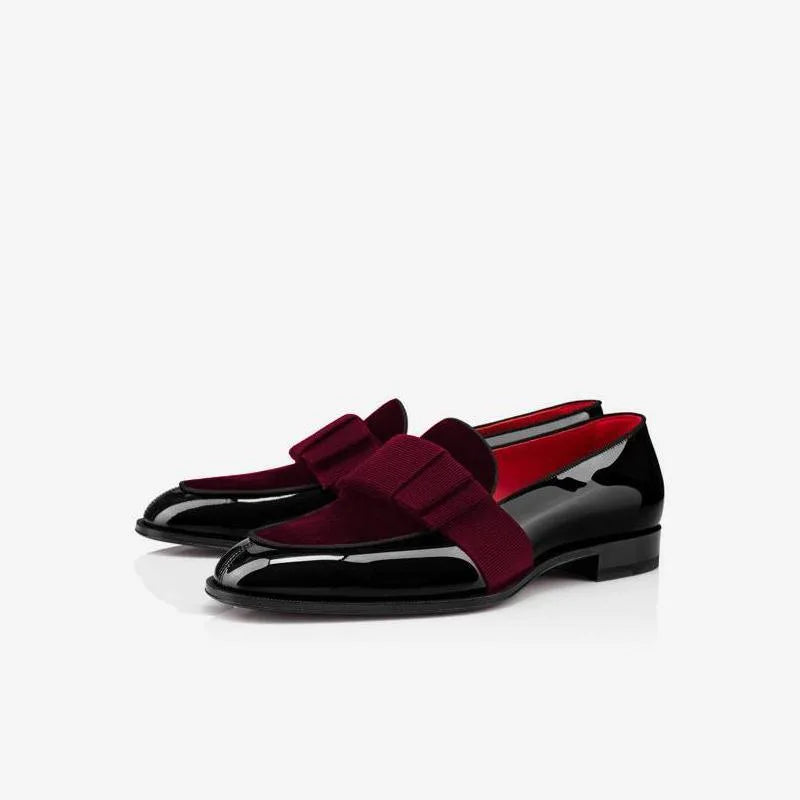 Side view of burgundy velvet and black patent leather loafers with grosgrain bow and red sole trim