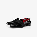 Pair of black patent leather loafers with burgundy velvet bow detail shown together