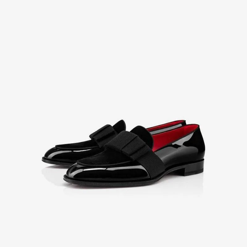 Pair of black patent leather loafers with burgundy velvet bow detail shown together