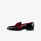 Close-up side view of white patent leather loafer with grosgrain bow on glossy upper