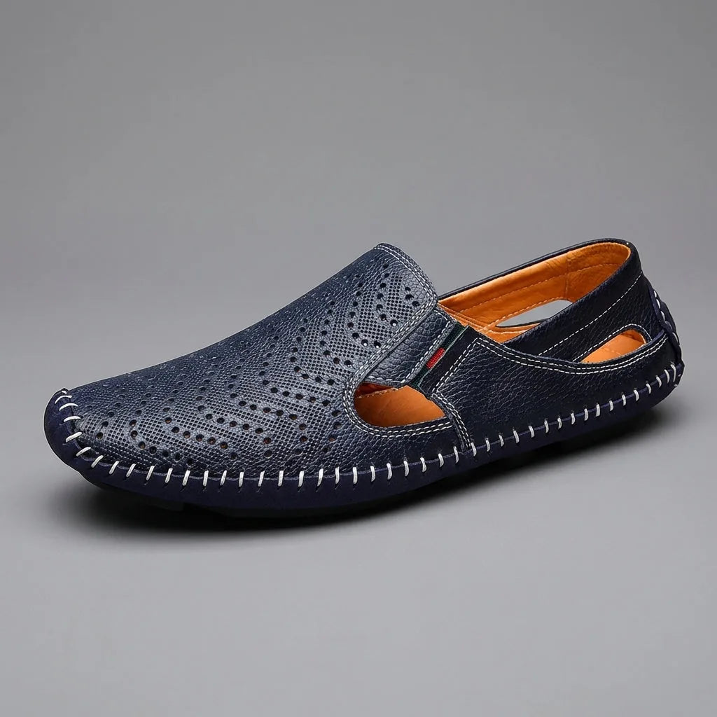 Side profile of a single navy perforated leather loafer with tan interior and whipstitched sole on grey background