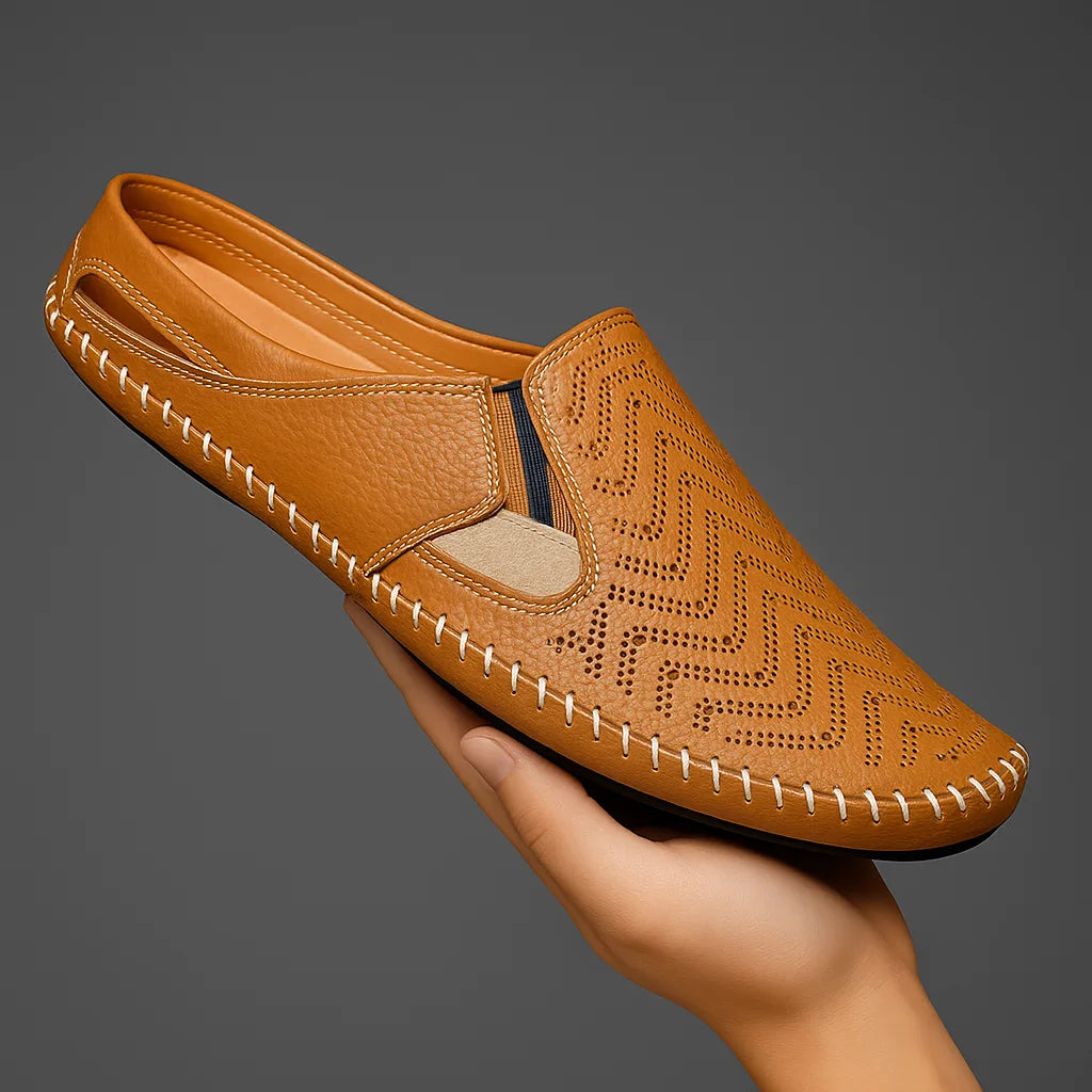 Tan perforated leather slip-on held in a hand, showing the matching cutout design and contrast stitching