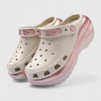 Cream clogs with metallic pink trim, perforated holes and cutout side vents on a ridged platform sole