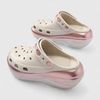 Side view of cream and metallic pink clog with perforated upper, ridged outsole and adjustable heel strap
