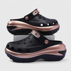 Side profile of black clog with rose gold heel strap, cutout side panels and thick ridged platform sole