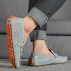 Sole view of a grey suede driving loafer worn on foot, showing textured orange rubber pebble outsole in full