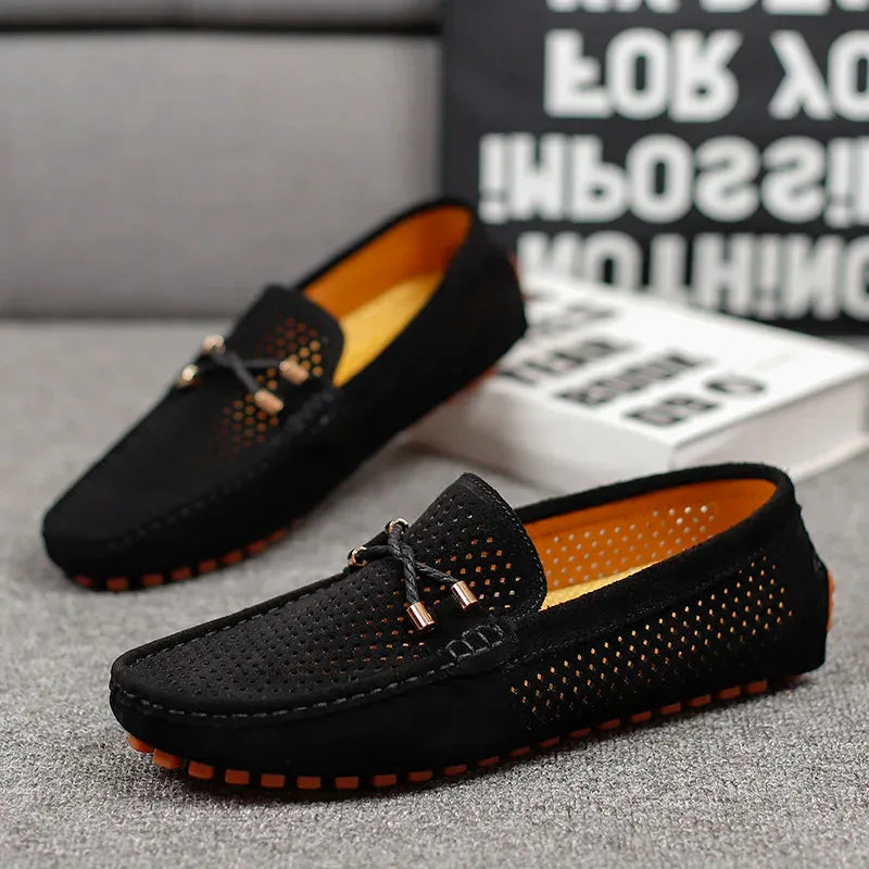 Front angled view of black suede loafer highlighting perforated vamp and gold-tipped bow lace