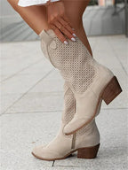 Beige suede perforated western boots in profile, showing the full shaft height and stacked heel