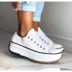 White canvas platform sneaker paired with cuffed light blue denim jeans, showing lace-up front and white sole