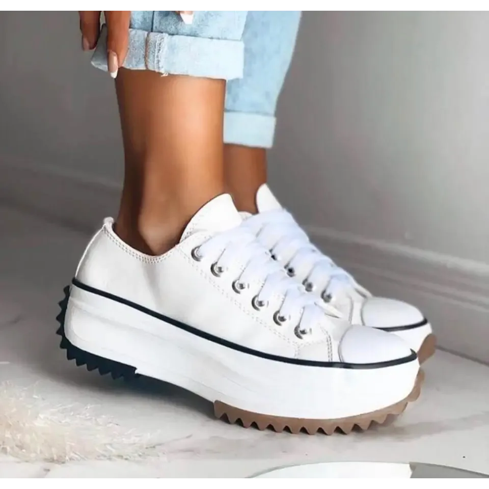 White canvas platform sneaker paired with cuffed light blue denim jeans, showing lace-up front and white sole