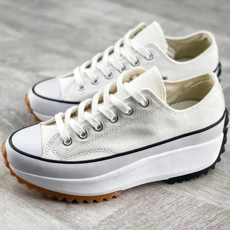 Pair of off-white canvas platform sneakers with gum rubber tread soles shown together on a wooden floor