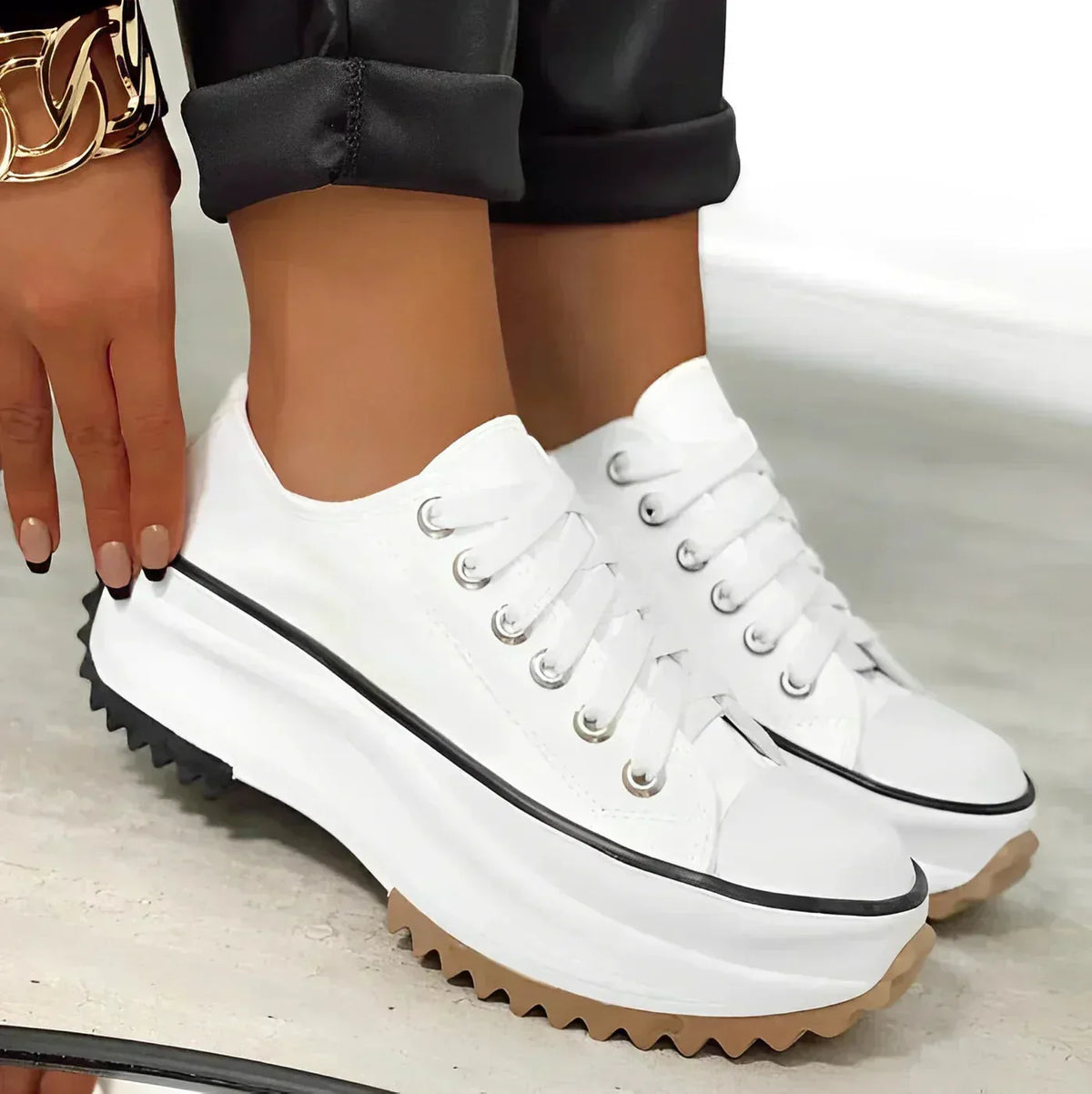 Close-up of beige lace-up platform sneaker with white rand and black chunky outsole on concrete flooring