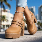 Tan platform Mary Jane clog heels with double crossover straps and buckles, worn with cuffed denim jeans