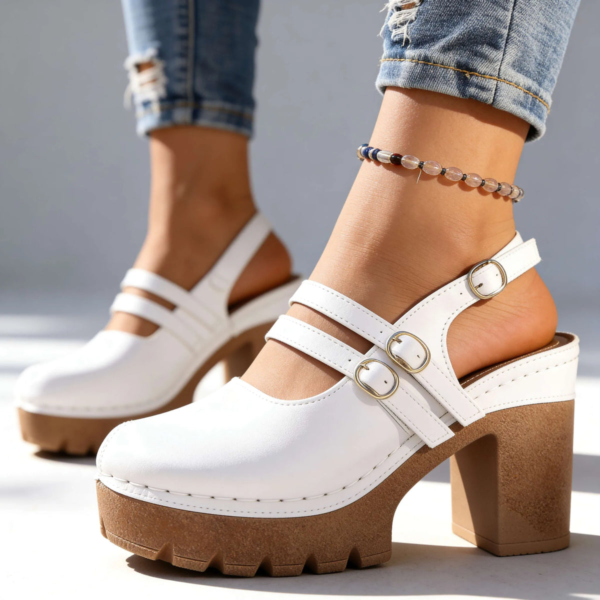 White slingback platform heels with double straps and gold buckles, side profile on light background