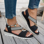 Side profile of black platform sandals worn with rolled denim, showing the padded sole and woven ankle strap
