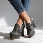 Studio image of grey platform slingback heels on crossed ankles, showing the sling strap and block heel from the side