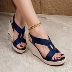 Close-up front view of light gold woven wedge sandals with adjustable ankle strap