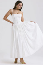 Front view of a pastel yellow floral corset midi dress with thin straps and a flowing pleated skirt