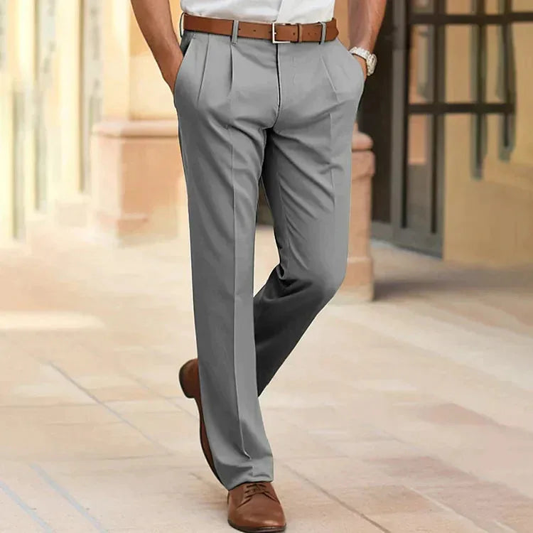 Grey tailored trousers with pleated front pockets, worn with a brown belt and lace-up shoes