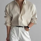 Detail shot of the cream pleated shirt fabric showing fine vertical ribbed texture and rolled cuffs