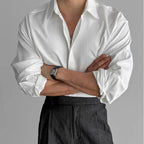 Man with arms crossed wearing a white pleated textured shirt, showing the relaxed oversized fit and cuff detail