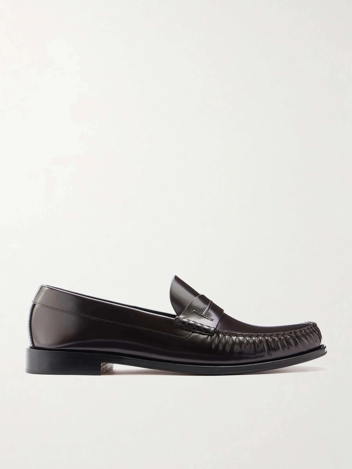 Side profile of a dark brown polished leather penny loafer with a moc toe seam and stacked block heel