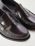 Close-up of two brown leather loafers showing the penny strap, moc stitching and glossy leather finish