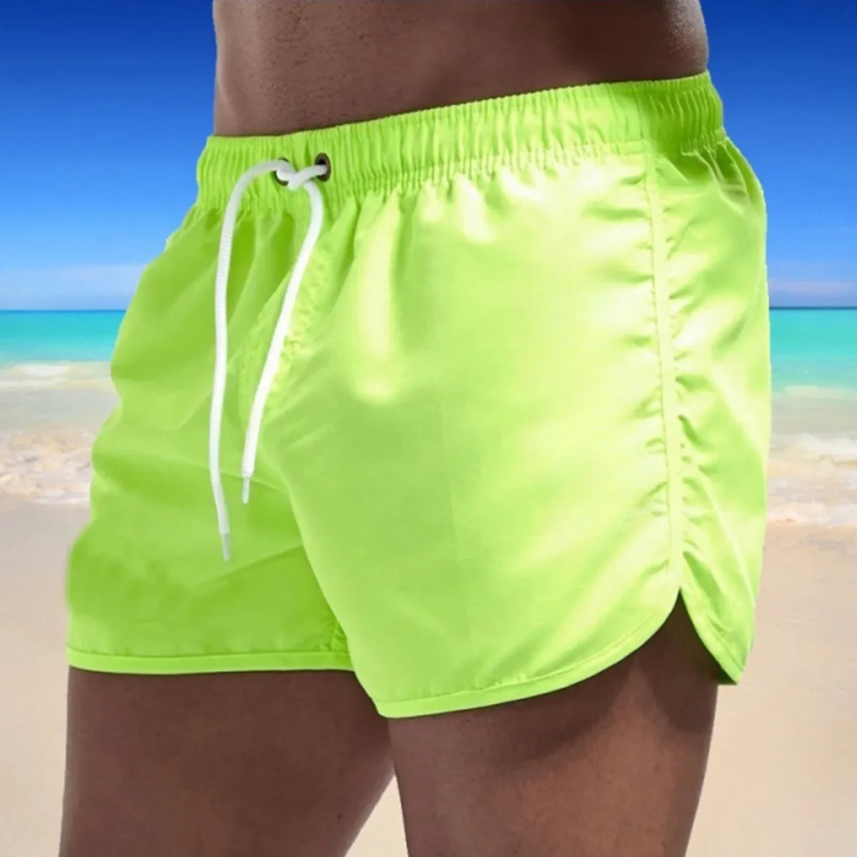 Side view of bright lime green swim shorts highlighting the glossy fabric sheen and curved hem