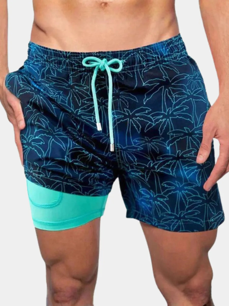 Close-up front view of navy blue swim shorts with light teal palm tree outline print and teal drawstring