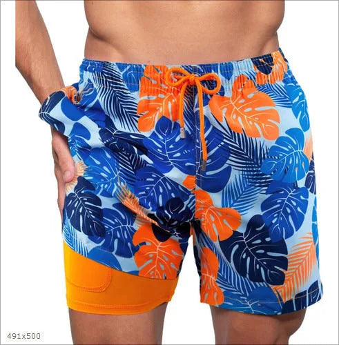 Side view of blue, navy and orange tropical leaf print swim shorts with solid orange hem panel