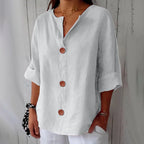White lightweight blouse with notch collar and wooden button placket, paired with white trousers